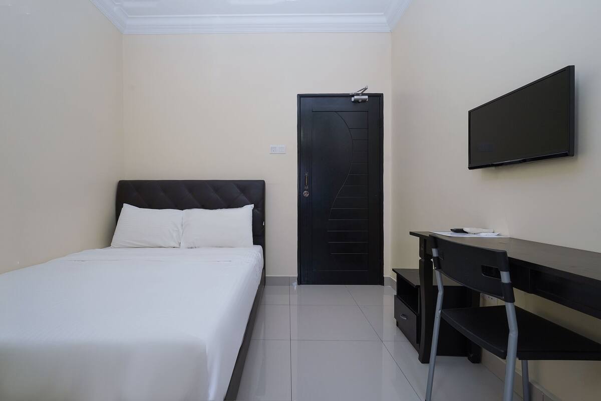 Ein Hotelzimmer mit Bett, Schreibtisch, Stuhl, Fernseher und einer Tür.