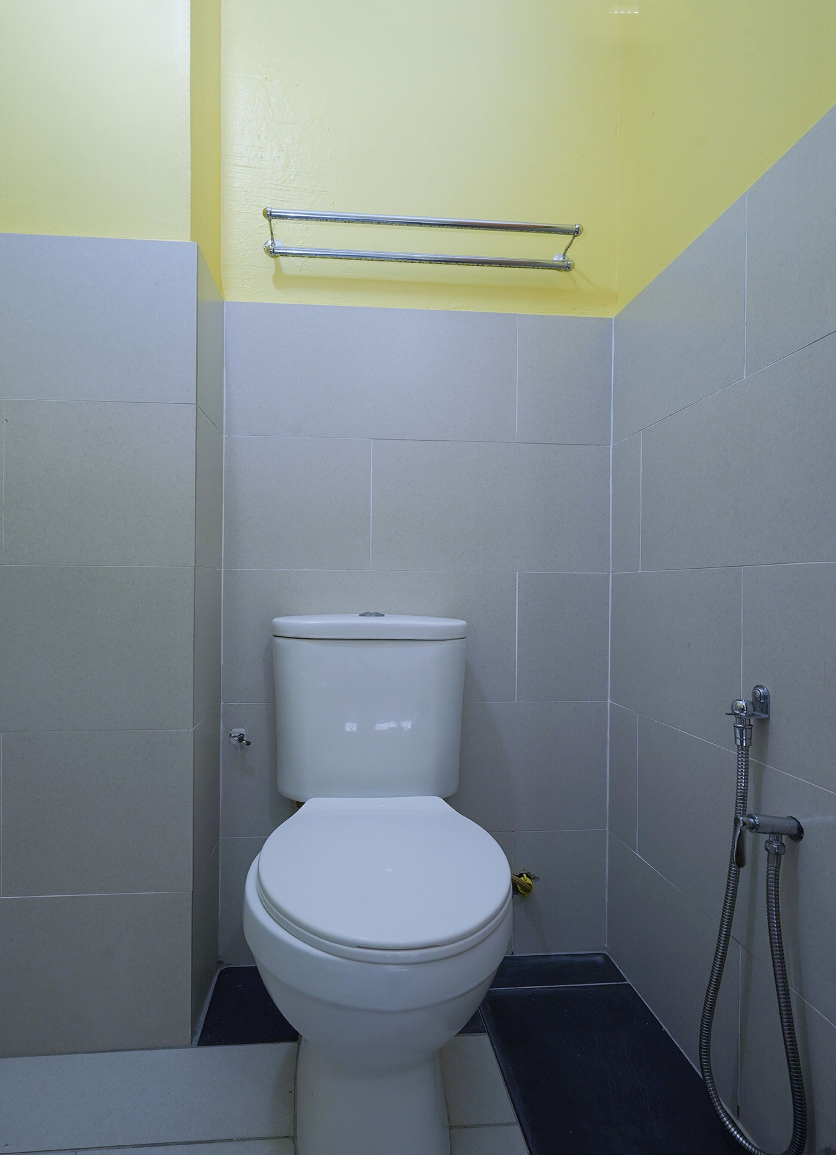 A small, compact bathroom with a toilet, a shower, and a towel rack.