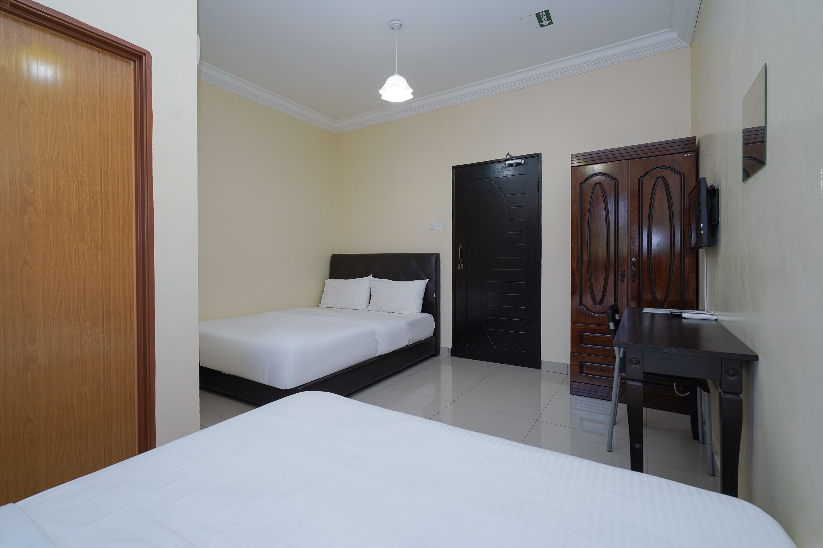 Una habitación de hotel con cama, escritorio, armario y puerta.