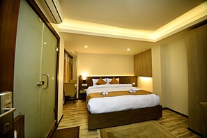 A hotel room with a large bed, bedside tables, a desk, and a wardrobe. - The Milestone Hotel (Kathmandu)
