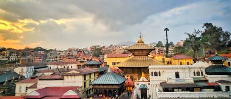 A cityscape with a prominent temple complex featuring multiple domes and a central staircase leading to a shrine.
