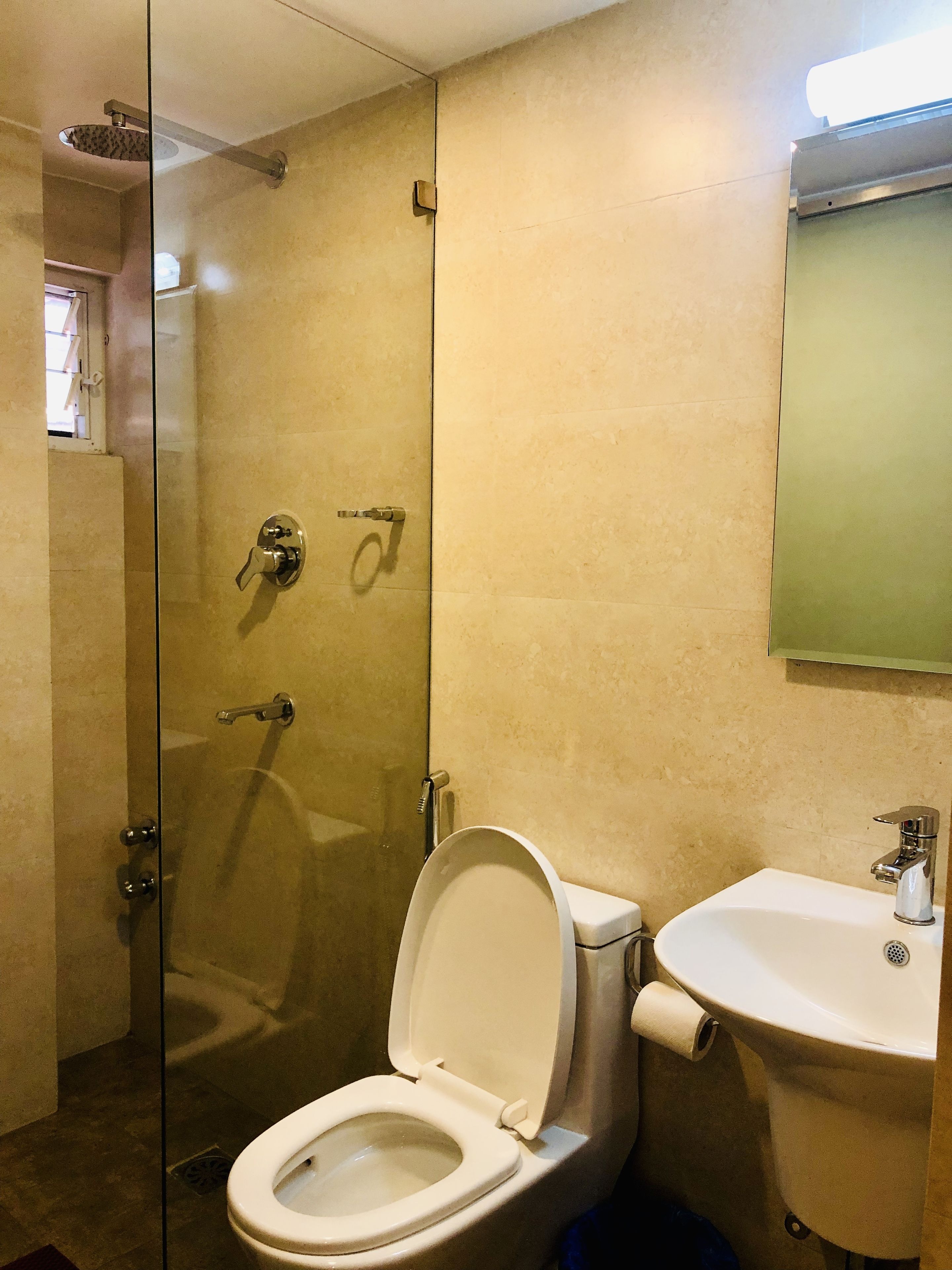 A bathroom with a glass-enclosed shower, a toilet, and a sink.