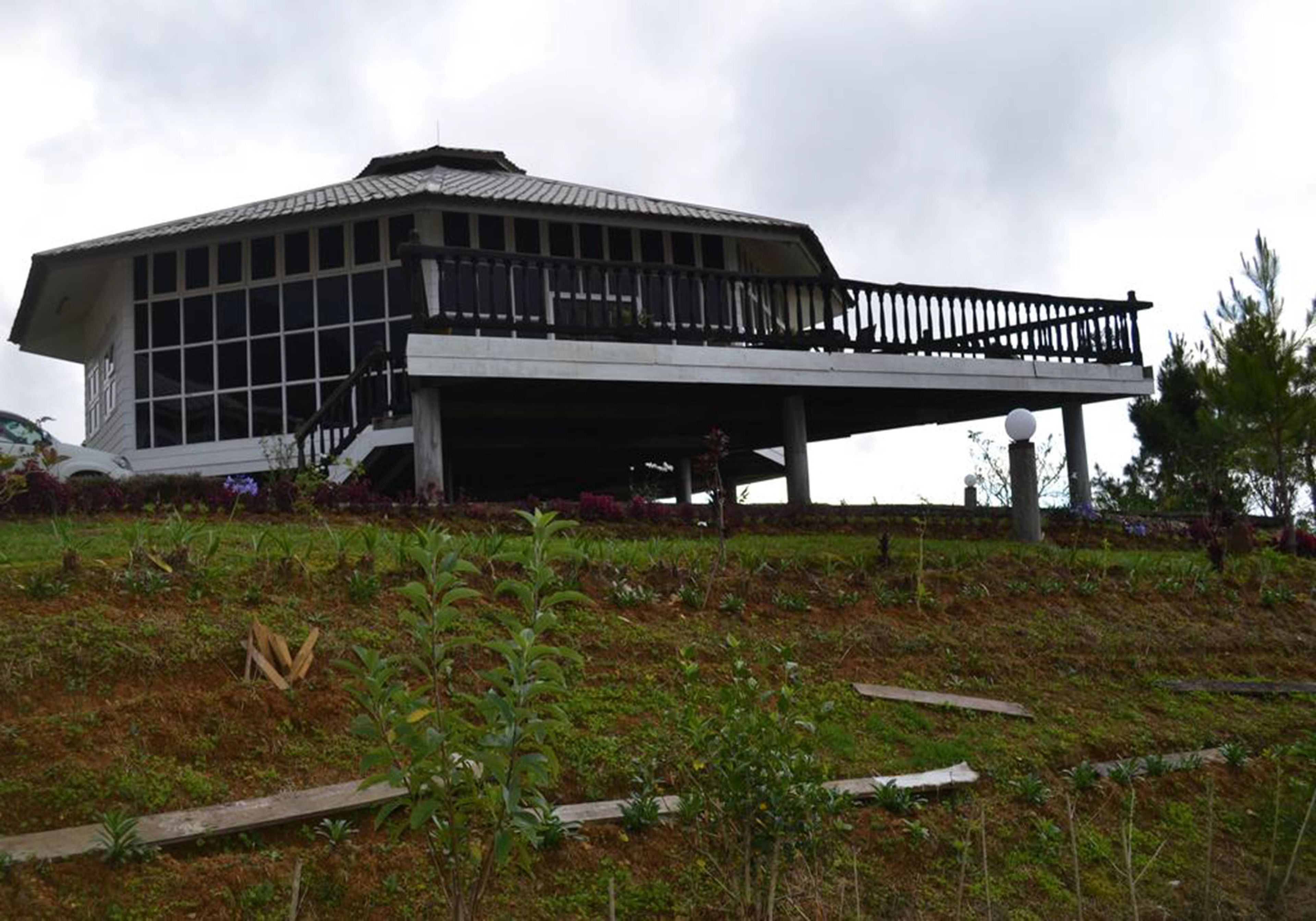 A modern building with a flat roof and large windows, featuring a covered walkway and a landscaped garden area.