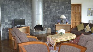 Una sala de estar con chimenea de piedra, muebles de madera y televisor.