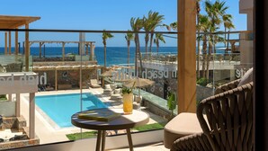 A balcony with a pool, lounge chairs, and a view of the sea. - High Beach White (Hersonissos)