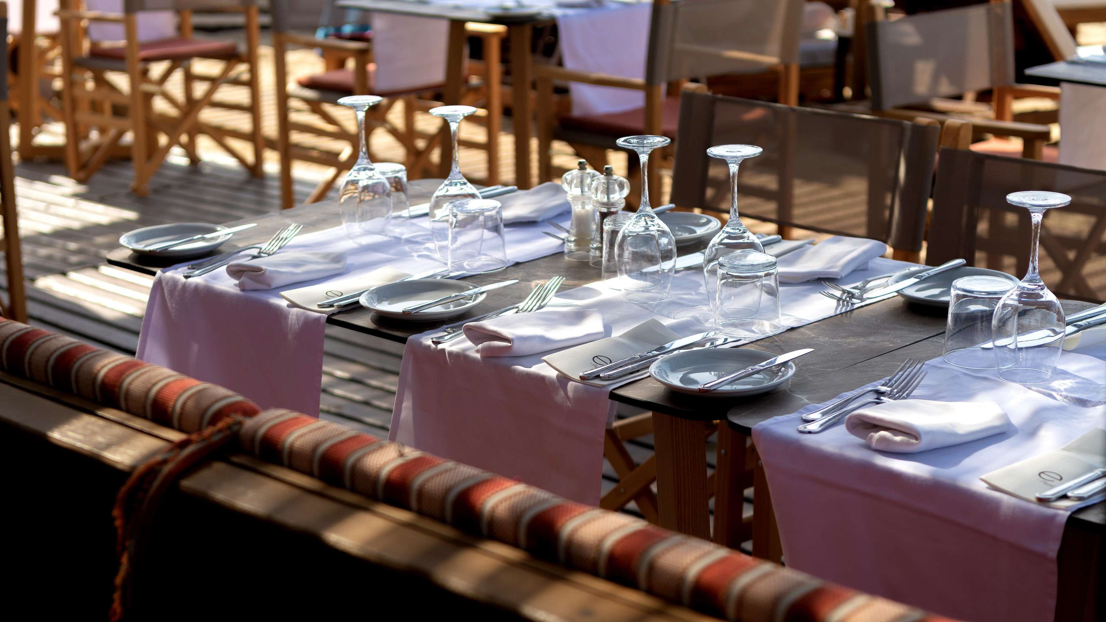 A dining table set with plates, cutlery, and wine glasses, covered with a white tablecloth.
