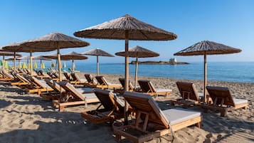Στην παραλία, λευκή άμμος, ξαπλώστρες (σεζλόνγκ), ομπρέλες θαλάσσης