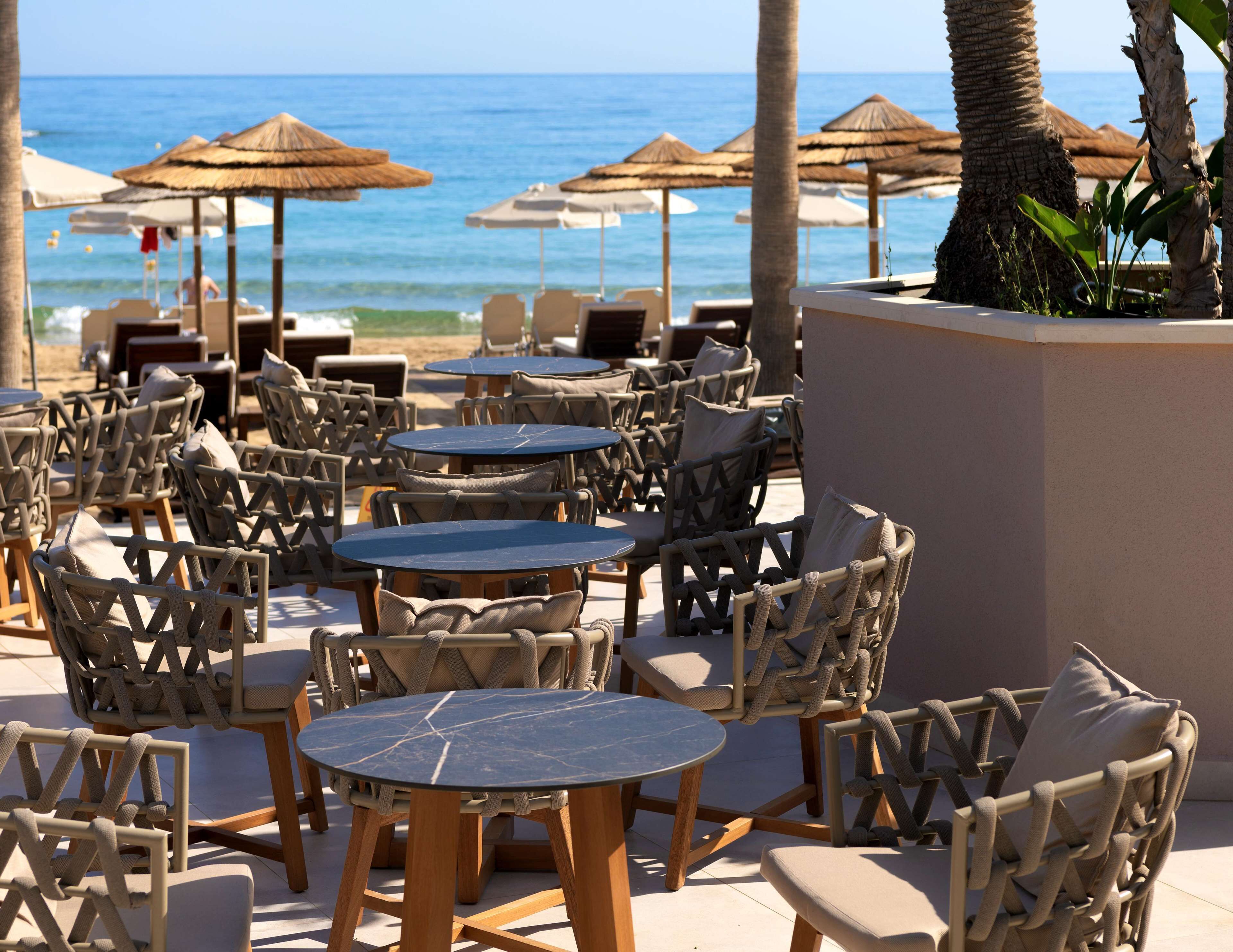 Outdoor seating with tables and chairs, umbrellas, and a view of the ocean.