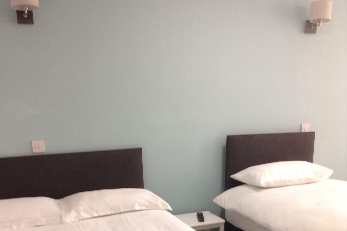 A hotel room with two beds, each with a headboard, a nightstand, and a lamp.