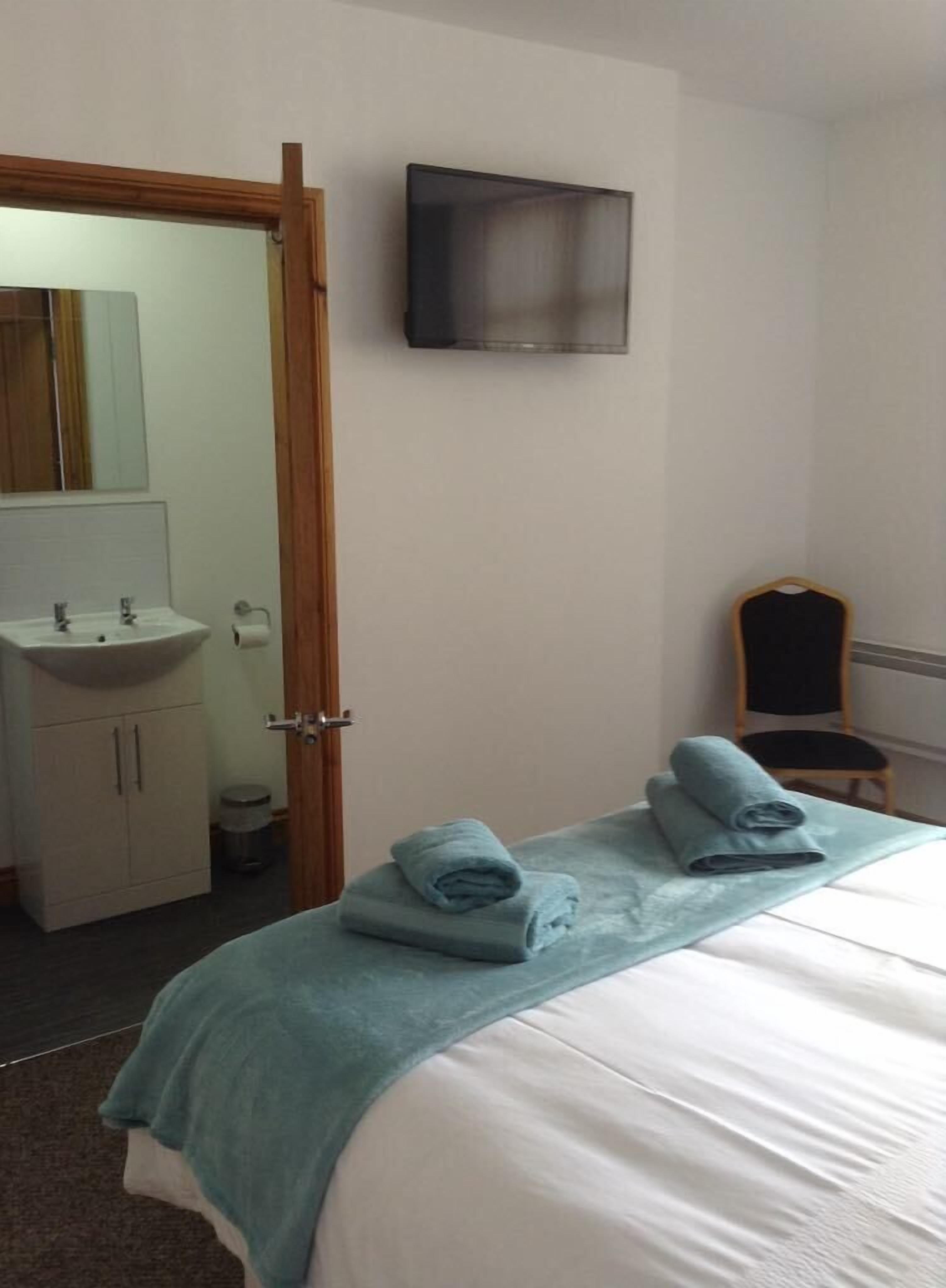 A bedroom with a bed, a sink, and a chair.
