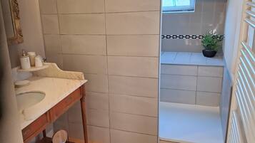 A bathroom with a marble sink, a wooden vanity, a mirror, and a potted plant.