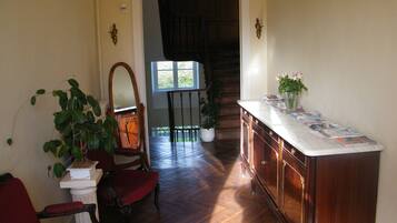 A spacious room with a wooden floor, a marble countertop, and a red chair.