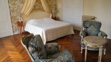 Un dormitorio con cama, una silla, una mesa y una mesita de noche.