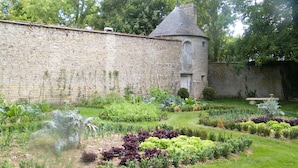 Un jardin avec un mur de pierre et une petite tour.