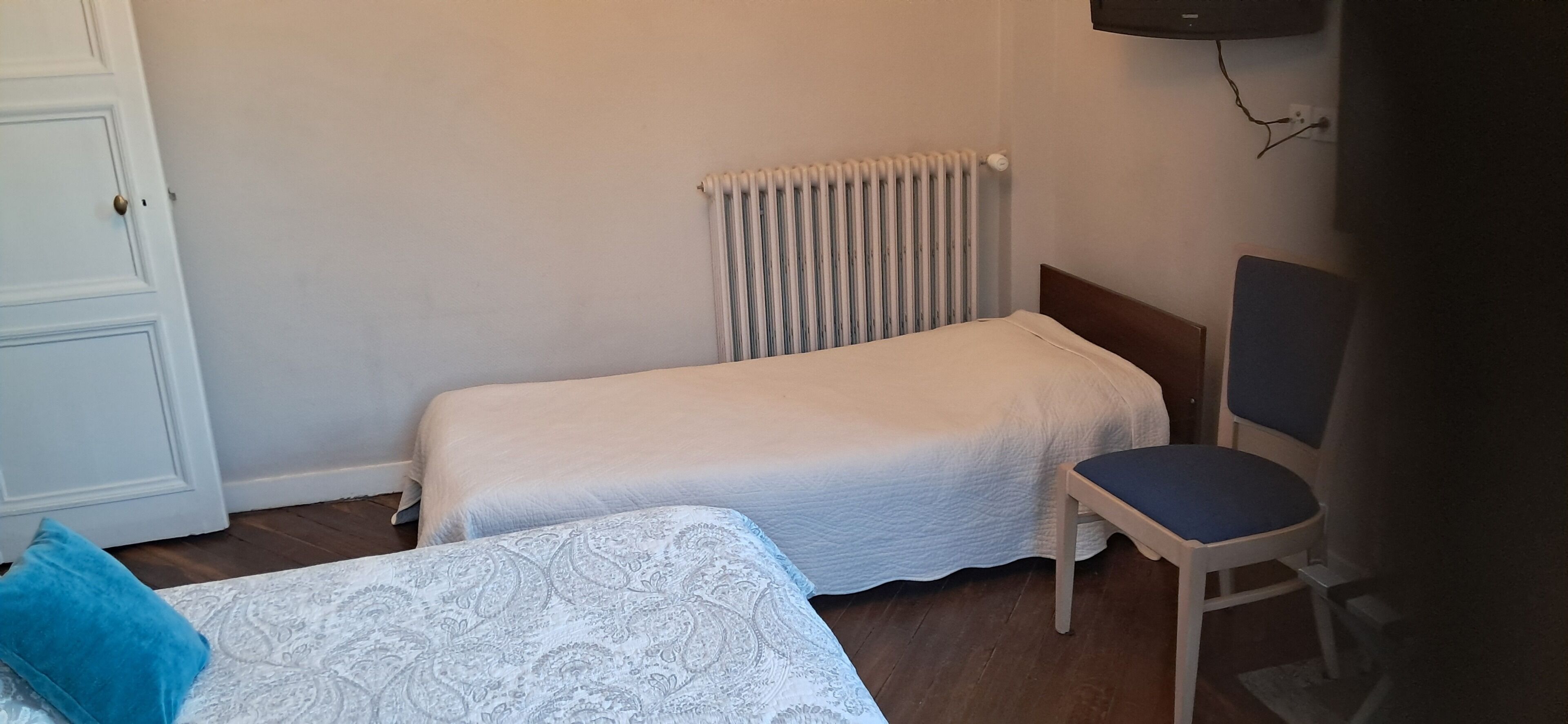 Een kleine kamer met een enkel bed, een stoel en een radiator.