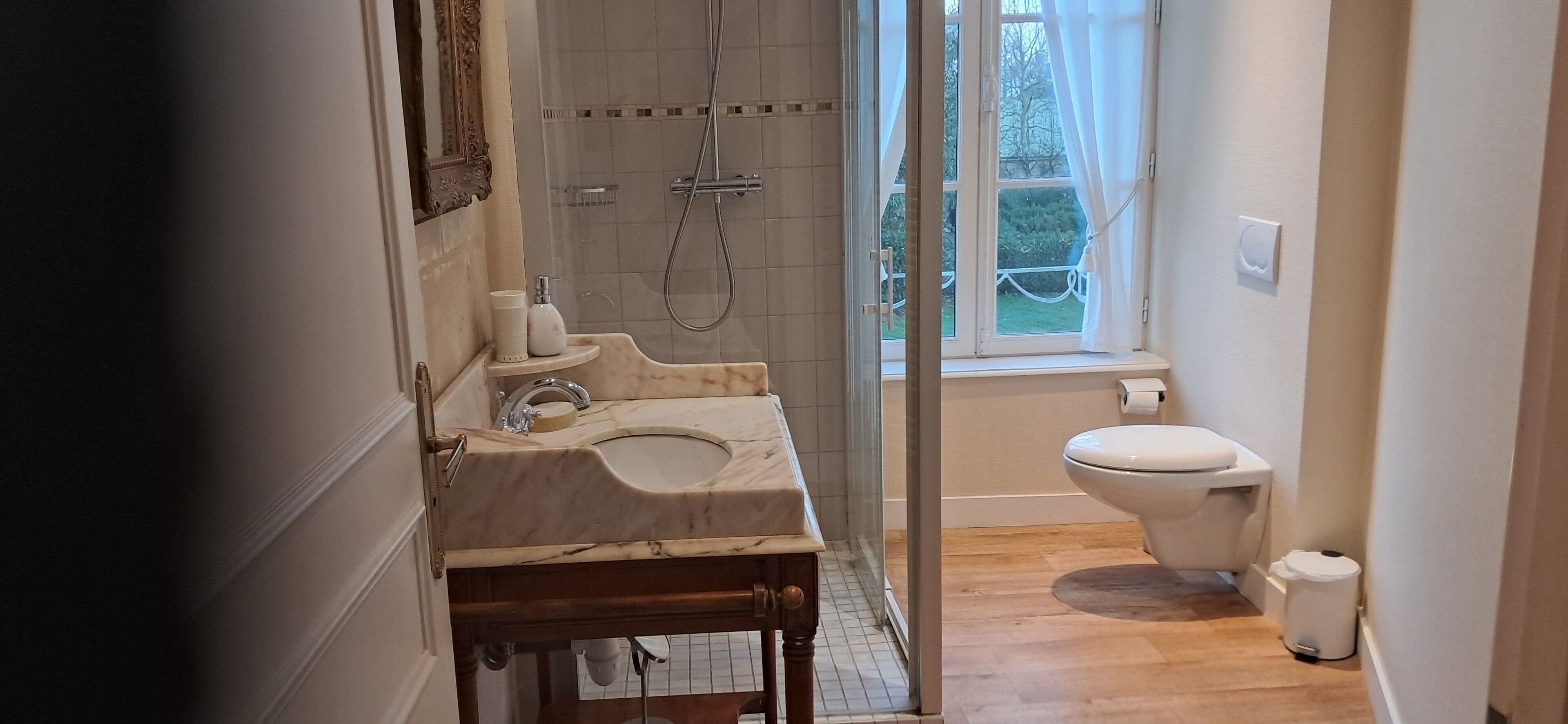 A bathroom with a marble sink, a shower, and a toilet.