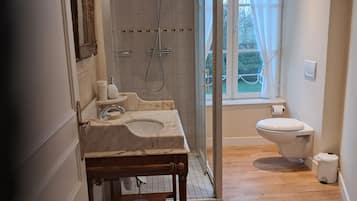 A bathroom with a marble sink, a shower, and a toilet.