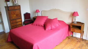 A bedroom with a large bed, two bedside tables with lamps, a dresser, and a chair.