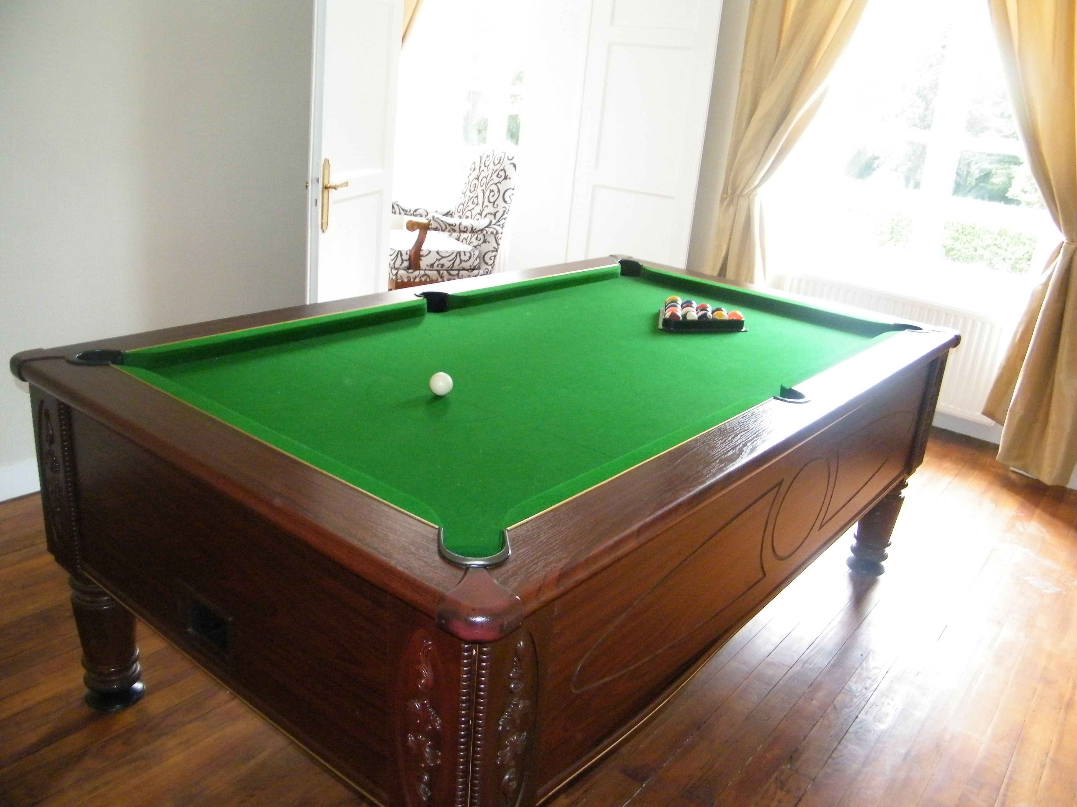 Une table de billard avec une boule blanche, un drap de jeu vert et un jeu de billes.
