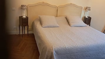 Un dormitorio con una cama grande, dos mesitas de noche y una lámpara a cada lado.