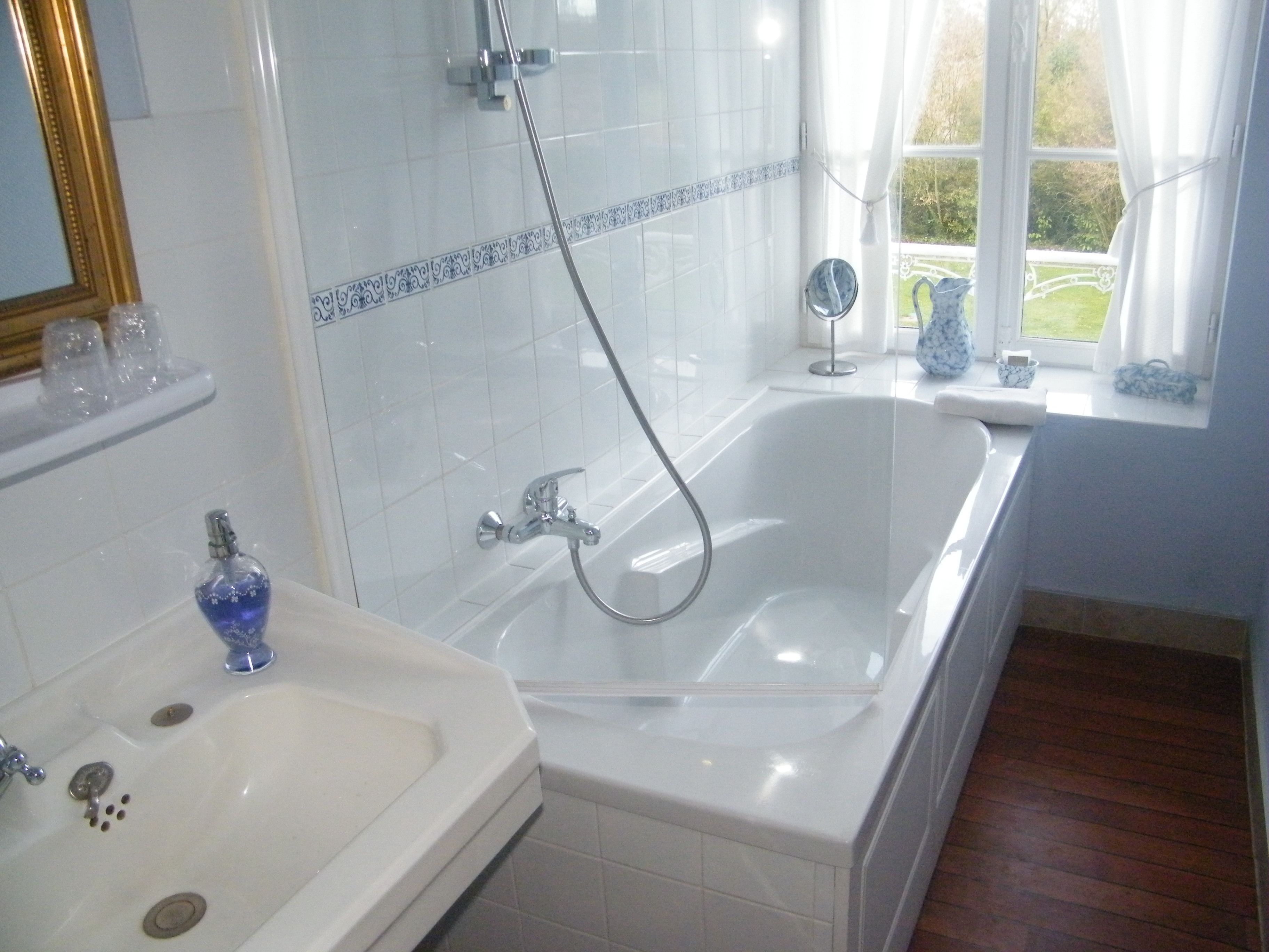 A bathroom with a bathtub, a sink, and a window with a view of the garden.