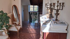 Une pièce avec un plancher en bois, un miroir, un chandelier et une plante.