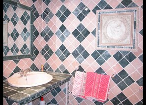 Un baño con lavamanos, espejo y azulejos estampados.