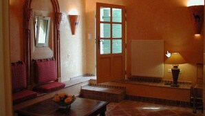 A cozy room with a wooden bench, a table with a flower vase, a window with a view, and a radiator. - Le Mazet De La Dame (Barbentane)