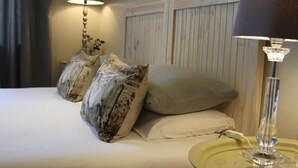 A neatly made bed with two decorative pillows, a bedside lamp, and a bedside table with a lamp. - Ripple Hill Hotel (Patensie)