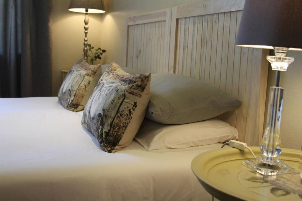 A neatly made bed with two decorative pillows, a bedside lamp, and a bedside table with a lamp.