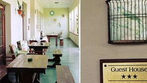 A dining area with wooden tables and benches, a wall-mounted sign indicating a guest house, and a window with a barred design. - Ripple Hill Hotel (Patensie)