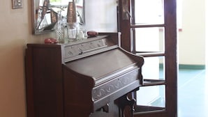 A wooden piano with a mirror above it, a door with glass panels, and a wooden floor. - Ripple Hill Hotel (Patensie)