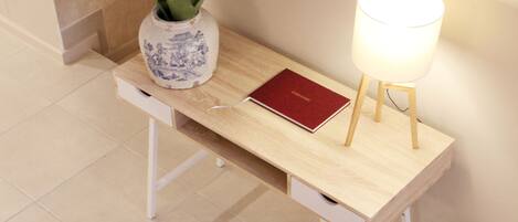 A wooden desk with a vase, a red book, and a lamp.