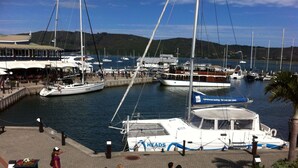 Marina con barcos amarrados, un café y una zona de estar con bancos.