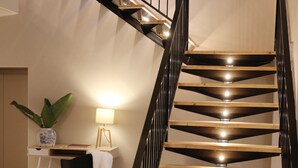 Una escalera moderna con peldaños de madera y barandillas negras, que conduce a un piso superior.