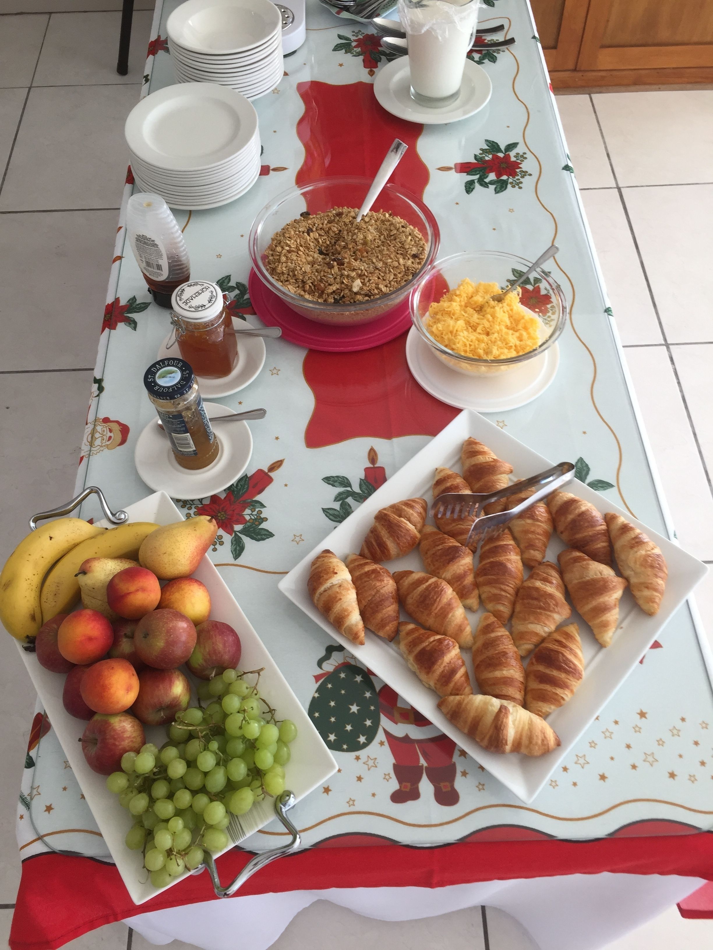 Een ontbijttafel met croissants, fruit en ontbijtgranen.