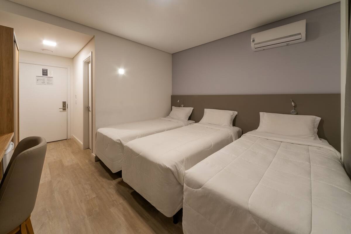 A hotel room with two single beds, a wooden desk, and a chair.