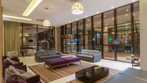 A modern hotel lobby with seating areas, a reception desk, and large windows offering views of the interior. -  Laghetto Rio Grande (Rio Grande)