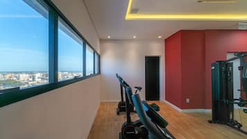 A gym with exercise equipment, large windows, and a city view.