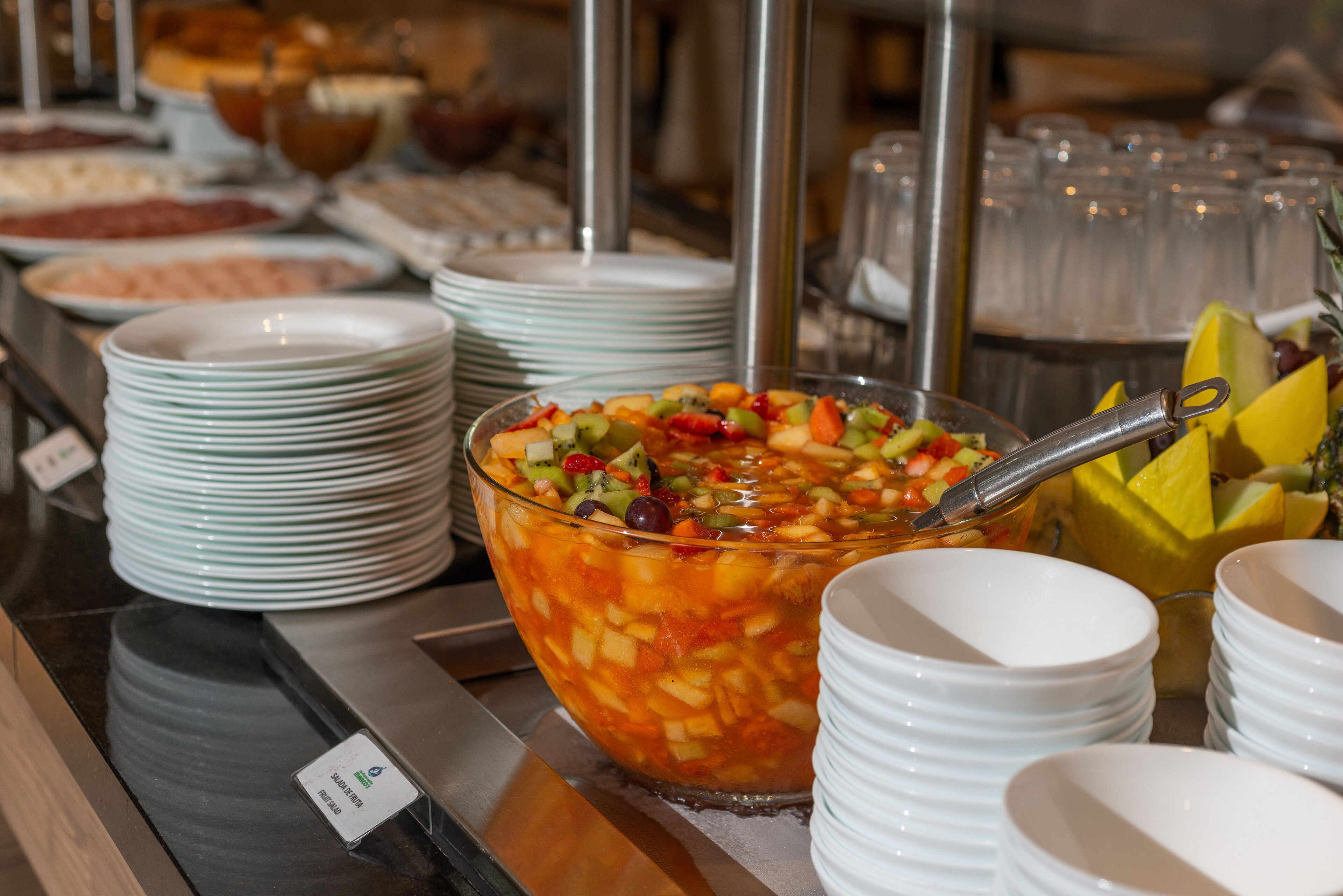 Ein Buffet mit verschiedenen Speisen und einer großen Schüssel Obstsalat.