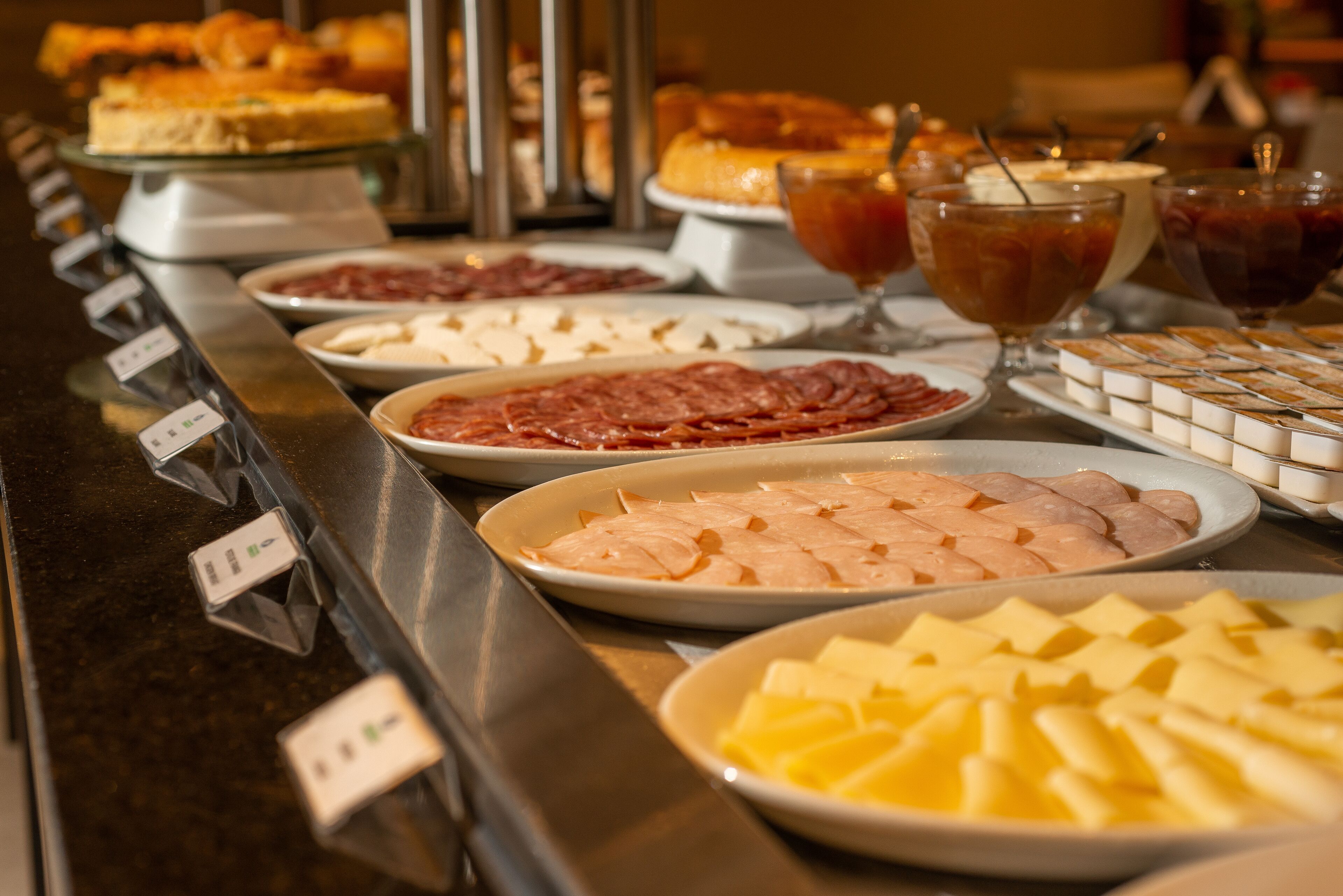 A buffet with various food items including meats, cheeses, and desserts.