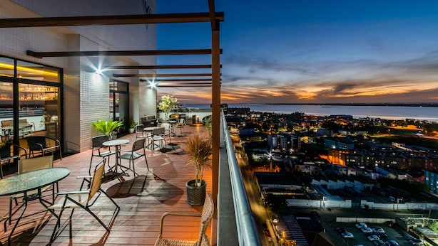 A rooftop terrace with outdoor seating, a view of the city, and a sunset. -  Laghetto Rio Grande (Rio Grande)