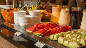 En buffet med et udvalg af frugter, herunder vandmelon og melon, samt flere drikkevarer.