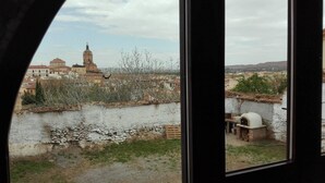 Vista a través de una ventana de un paisaje urbano con un río, un muro de piedra y un edificio con una torre.