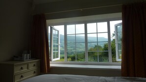 A bedroom with a large window, a bed, and a nightstand. - The Kestrel B&B (Crickhowell)