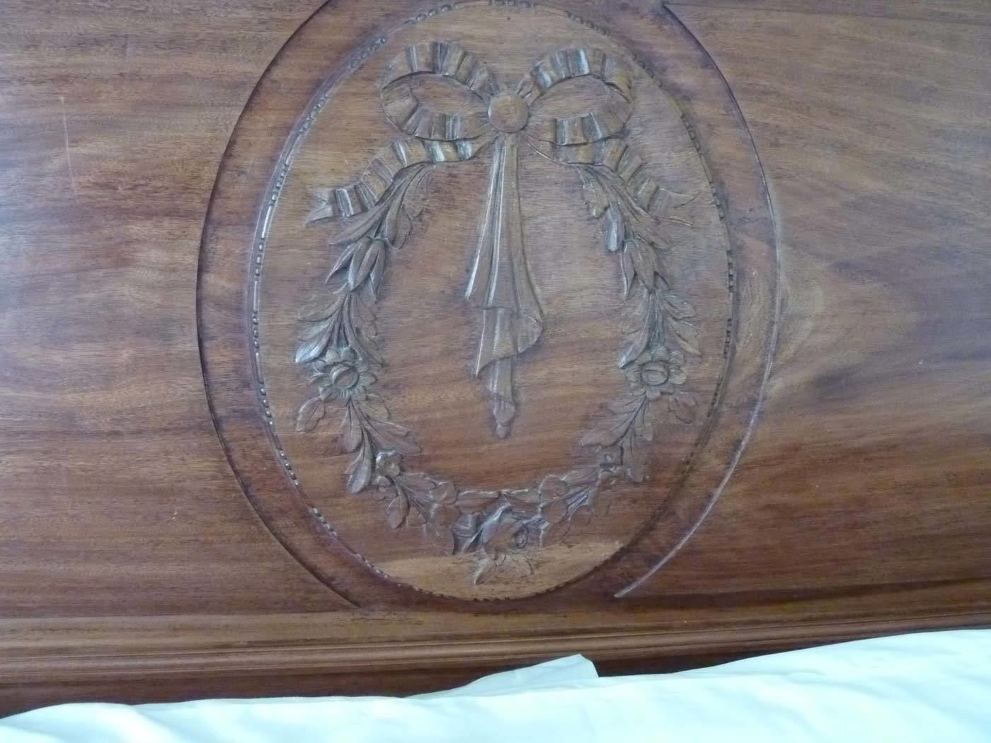 Ein hölzernes Objekt mit ovalem Design, das ein zentrales Emblem in einem Lorbeerkranz zeigt.