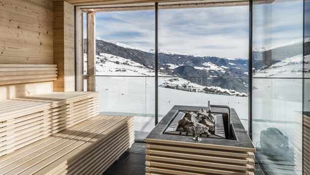 A wooden sauna with a stone hot tub and a panoramic mountain view. - Hotel Ambet (Rio di Pusteria)