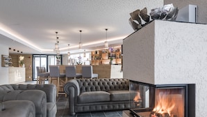 A modern living room with a fireplace, a sofa, and a dining area with chairs and a table. - Hotel Ambet (Rio di Pusteria)