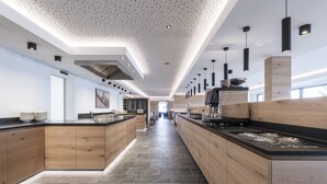 A modern kitchen with wooden cabinets, a central island, and pendant lighting. - Hotel Ambet (Rio di Pusteria)