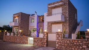 A modern stone building with balconies, a gated entrance, and a sign indicating a spa. - G&K Stone Suites (Rhodes)